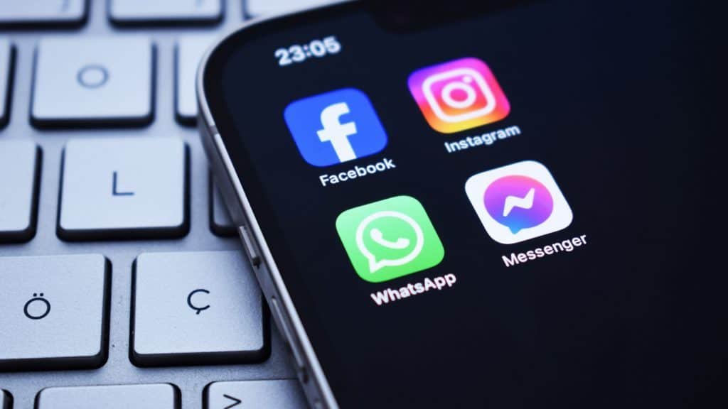 Ícones dos aplicativos do Facebook, Instagram, WhatsApp e Messenger, redes sociais da Meta, em tela inicial de um iPhone colocado sobre teclado de notebook