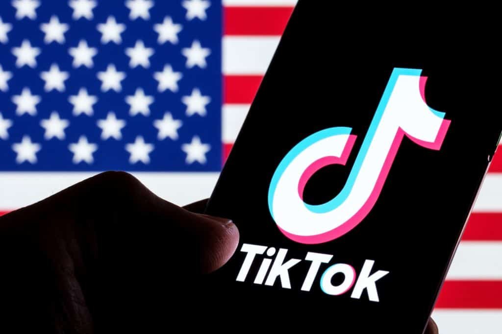 Bandeira dos EUA à esquerda; à direita, logo do TikTok em um smartphone