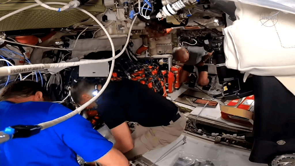 Astronautas mexendo na área interna da espaçonave