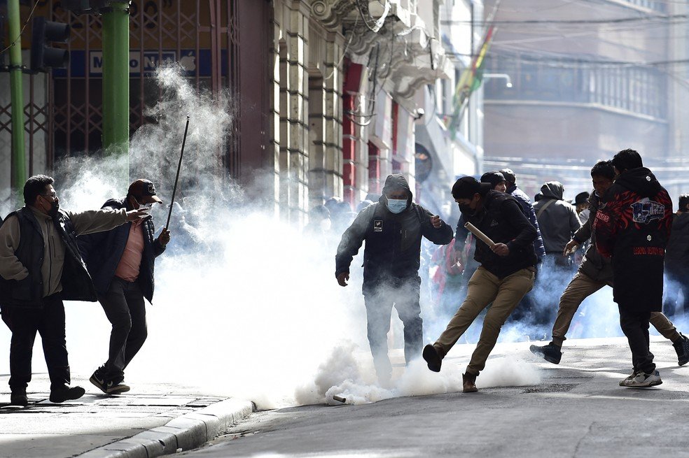 Manifestantes chutam bomba de gás lacrimogêneo lançada por policiais em meio a protestos em La Paz, na Bolívia.