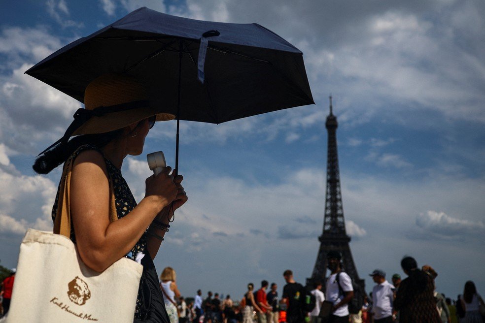 Uma mulher se protege do sol com um guarda-chuva na Praça do Trocadero, perto da Torre Eiffel, enquanto as temperaturas sobem em Paris durante a segunda onda de calor que afeta grande parte da França.