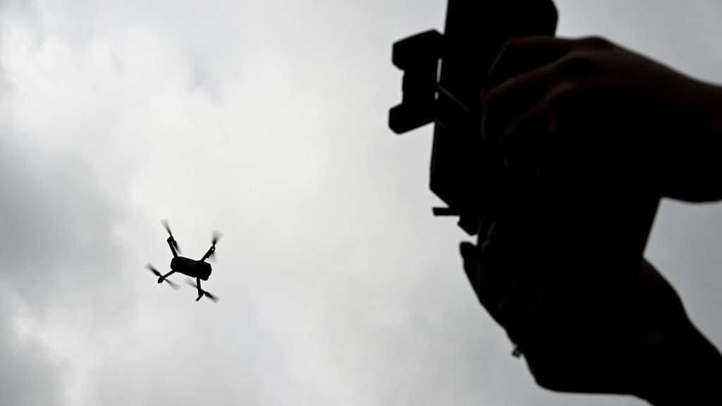 Silhueta de pessoa segurando controle e de drone no céu