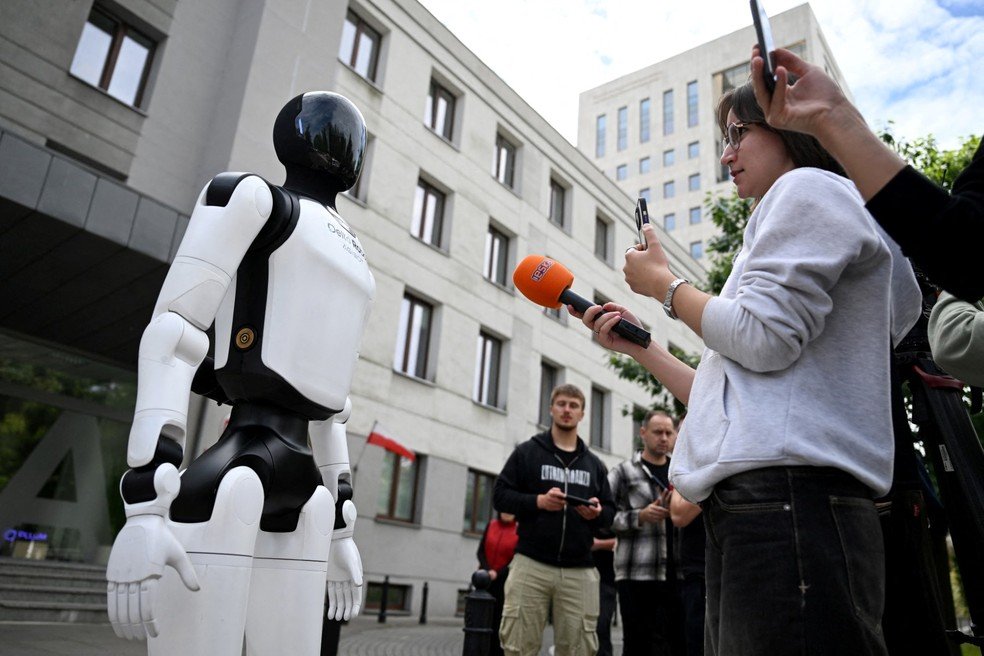 Um robô humanoide da Delta Robots Agibot concede entrevista a um jornalista durante manifestação que pede a regulamentação do desenvolvimento da inteligência artificial, em Varsóvia, em 7 de setembro de 2026.